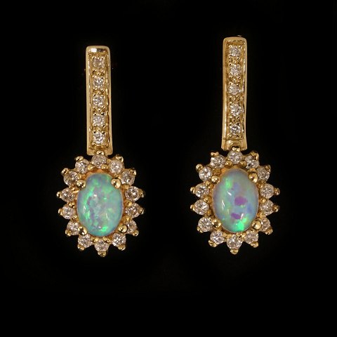 Pair of 14kt gold earrings each with an oval opal 
and 19 diamonds of ca. 0,015ct. H: 24mm. W: 10mm