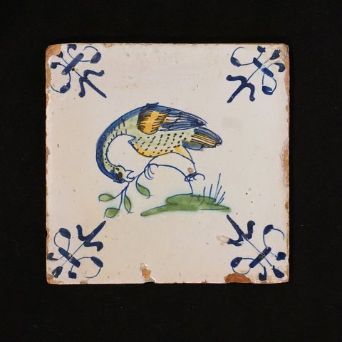 A 17th century polychrome decorated tile with a 
bird. Circa 1620-40. Size: 13x13cm