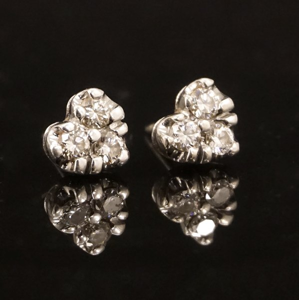 Et par hjerteformede 14kt hvidguldsørestikker med tre diamanter i hver. I alt ca. 0,6ct. Låse 8kt hvidguld