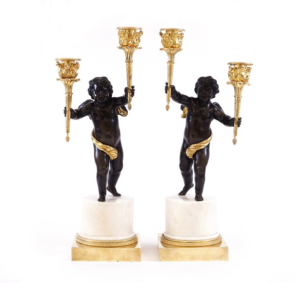 A Pair of early Empire fire gilt bronze candelabra with two putti each carrying 
two candlesticks. France circa 1795. H: 45cm